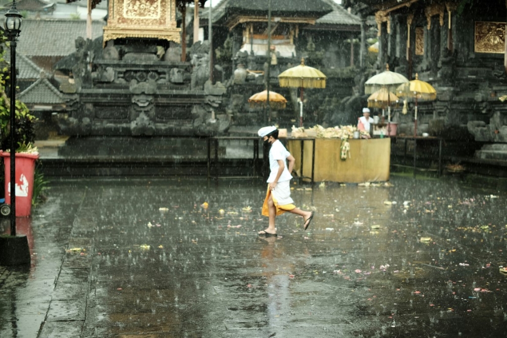 A person walking through a temple courtyard in the rain