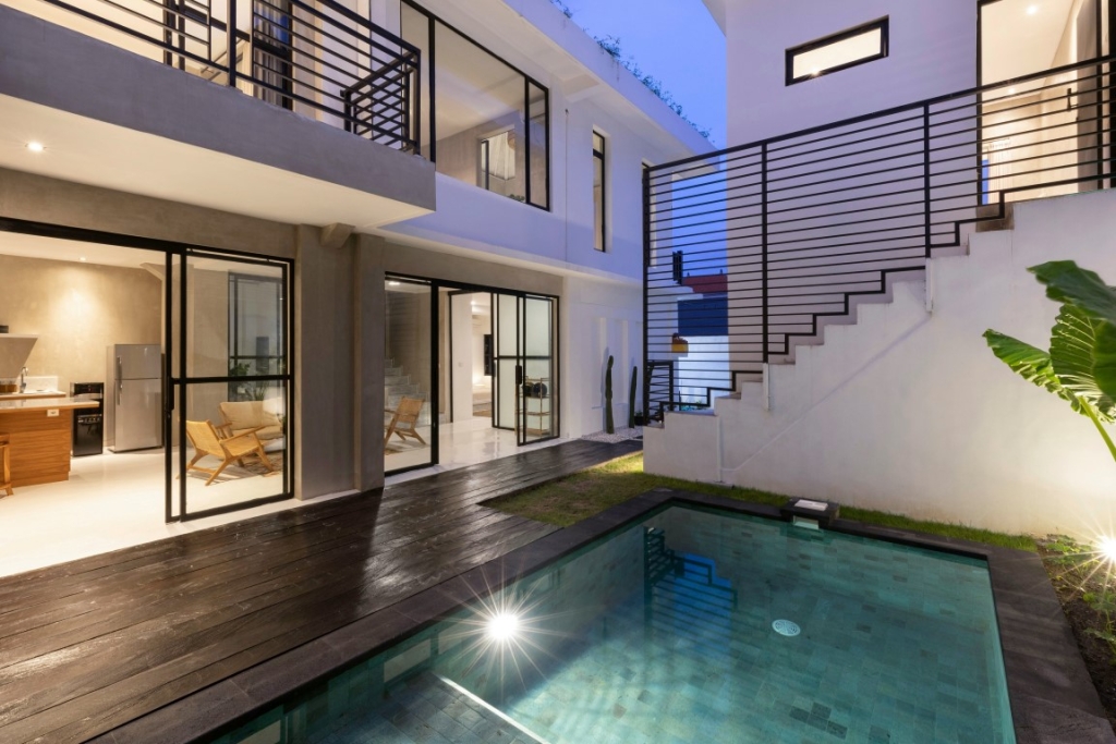 A modern villa with a small pool at night.