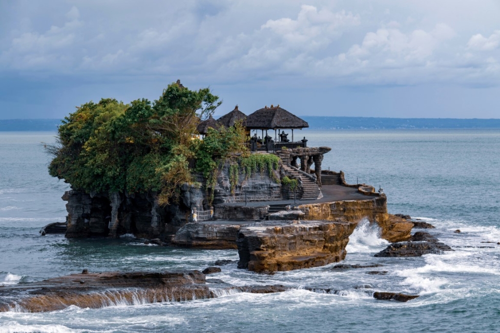 A temple on a rocky island surrounded by the ocean.